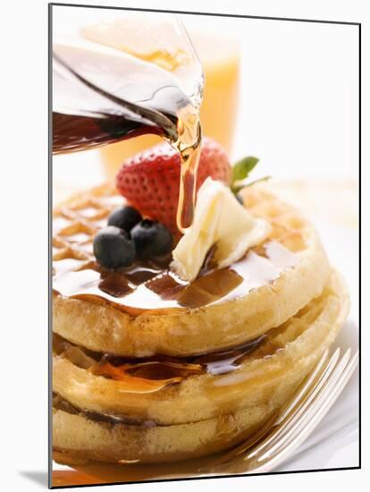 Pouring Maple Syrup over Waffles with Butter and Berries-null-Mounted Photographic Print