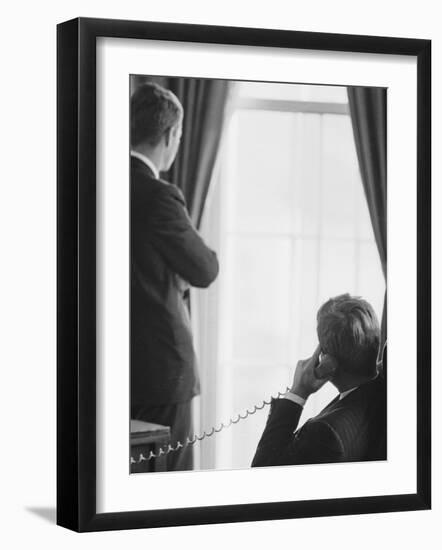 Pres. John F. Kennedy on Telephone While Brother, Attorney General Robert F. Kennedy Stands Nearby-Art Rickerby-Framed Premium Photographic Print
