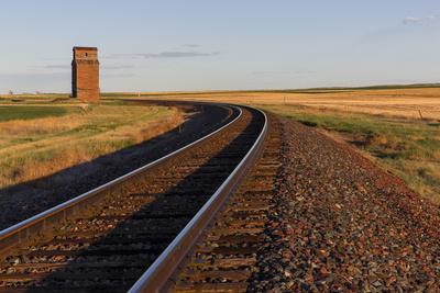 https://imgc.allpostersimages.com/img/posters/railroad-tracks-lead-to-old-wooden-granary-in-collins-montana-usa_u-L-PRPZW90.jpg?artPerspective=n