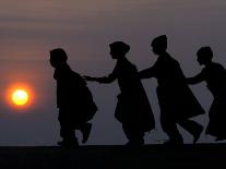 A Camel Stands as Villagers Walk at Sunrise at the Annual Cattle Fair in Pushkar, November 3, 2006-Rajesh Kumar Singh-Photographic Print