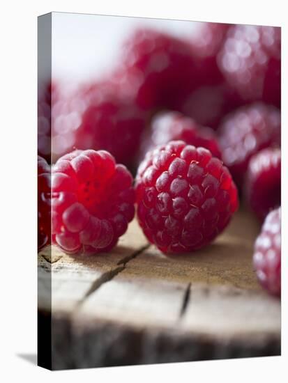 Raspberries on a Wooden Surface-Martina Schindler-Stretched Canvas