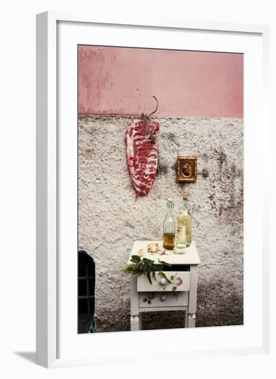 Raw Pork Ribs Hanging on the Wall of a House, Next to a A Gold-Framed Picture-Maria Brinkop-Framed Photographic Print