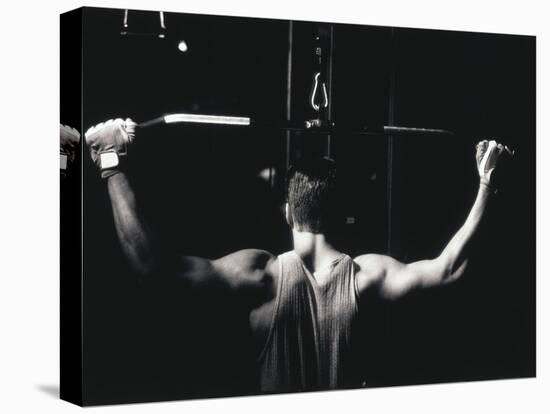 Rear View of a Young Man Exercise on a Lateral Pull-Down Weight Machine-null-Stretched Canvas