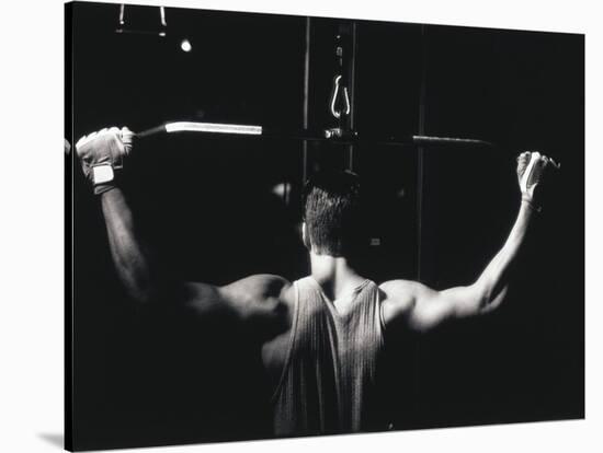 Rear View of a Young Man Exercise on a Lateral Pull-Down Weight Machine-null-Stretched Canvas