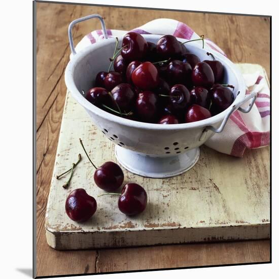 Red Cherries in a Colander on an Old Wooden Chopping Board-Michael Paul-Mounted Photographic Print
