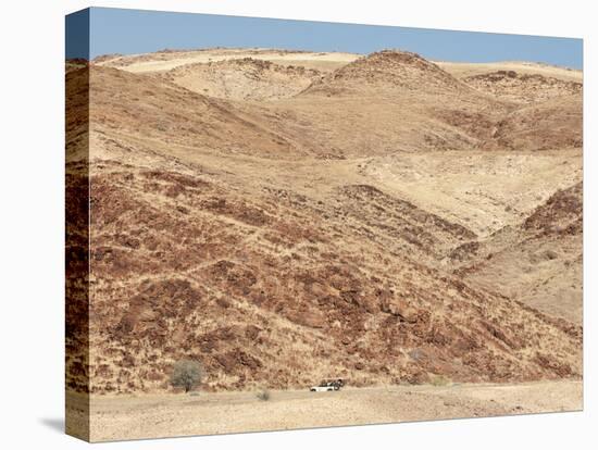 Red Rocky Landscape with Jeep in Distance, Purros Conservancy Wilderness, Kaokoland, Namibia-Kim Walker-Stretched Canvas