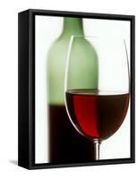 Red Wine Glass with Half-Full Wine Bottle in Background-Joerg Lehmann-Framed Stretched Canvas