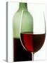 Red Wine Glass with Half-Full Wine Bottle in Background-Joerg Lehmann-Stretched Canvas