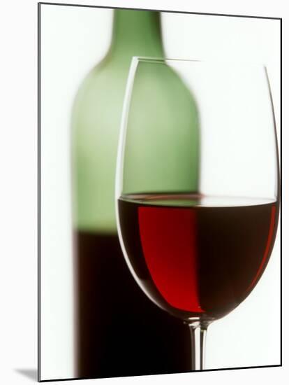 Red Wine Glass with Half-Full Wine Bottle in Background-Joerg Lehmann-Mounted Photographic Print