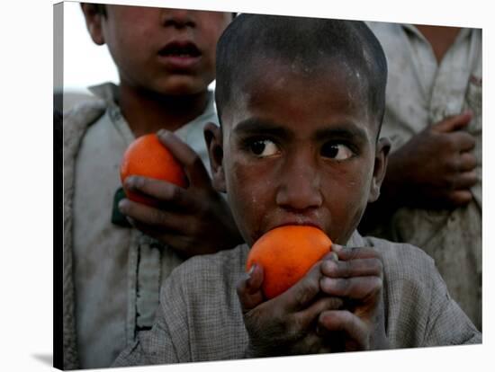 Refugee Boys Eat Tangerines at a Small Refugee Camp-null-Stretched Canvas