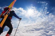 Mountaineer Walking up along a Snowy Ridge with the Skis in the Backpack. in Background a Shiny Bri-Roberto Caucino-Stretched Canvas