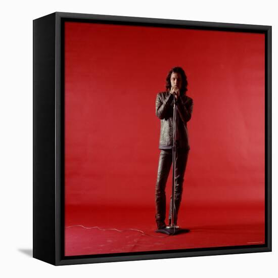 Rock Star Jim Morrison of the Doors Holding Microphone Alone as He Stands Against a Red Backdrop-Yale Joel-Framed Stretched Canvas