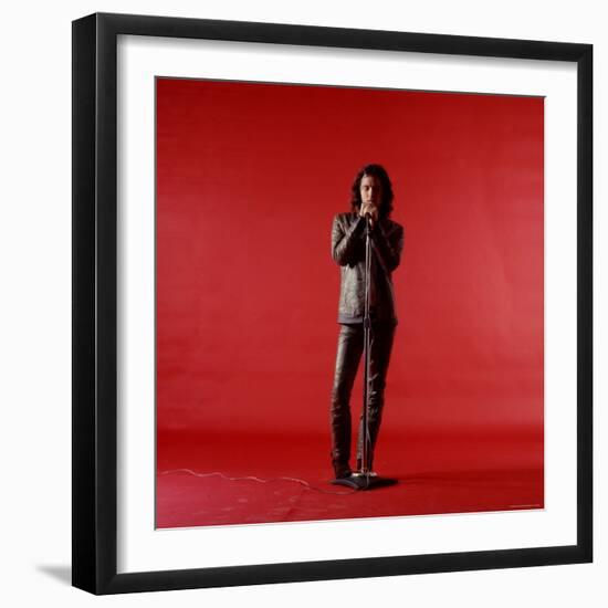 Rock Star Jim Morrison of the Doors Holding Microphone Alone as He Stands Against a Red Backdrop-Yale Joel-Framed Premium Photographic Print