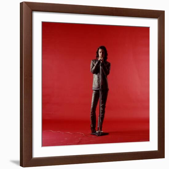 Rock Star Jim Morrison of the Doors Holding Microphone Alone as He Stands Against a Red Backdrop-Yale Joel-Framed Premium Photographic Print