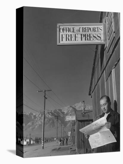 Roy Takeno, editor of Manzanar Free Press, reading the paper at the Manzanar War Relocation Center-Ansel Adams-Stretched Canvas