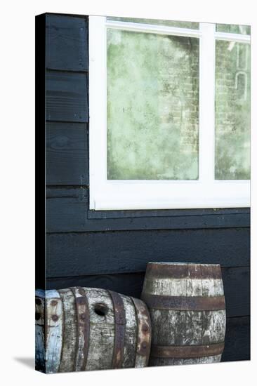 Rustic Barrels Lined Up Along an Old House Below a Window-Sheila Haddad-Stretched Canvas