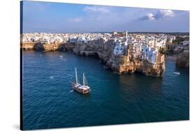 Sail boat anchored in the water off the white village of Polignano a Mare at sunset, Bari province-Paolo Graziosi-Stretched Canvas