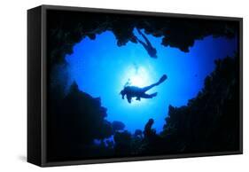 Scuba Divers Descend into an Underwater Cavern. Silhouettes against Sunburst-Rich Carey-Framed Stretched Canvas