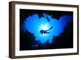 Scuba Divers Descend into an Underwater Cavern. Silhouettes against Sunburst-Rich Carey-Framed Photographic Print