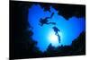Scuba Divers Descend into an Underwater Cavern. Silhouettes against Sunburst-Rich Carey-Mounted Photographic Print