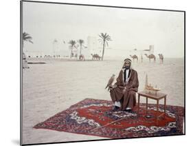 Sheikh Shakhbut Bin Sultan Al Nahyan Sitting in Front of His Palace Holding a Falcon, 1963-Ralph Crane-Mounted Photographic Print