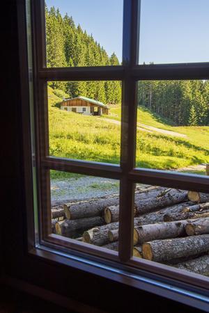 View out a window toward a cabin nestled in the hills of the Austrian Alps