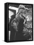 Shopper Looking at Tiny Figurine as She Holds Her Yorkshire Terrier in Arms at Saks Fifth Avenue-Yale Joel-Framed Stretched Canvas