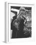 Shopper Looking at Tiny Figurine as She Holds Her Yorkshire Terrier in Arms at Saks Fifth Avenue-Yale Joel-Framed Photographic Print