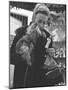 Shopper Looking at Tiny Figurine as She Holds Her Yorkshire Terrier in Arms at Saks Fifth Avenue-Yale Joel-Mounted Photographic Print