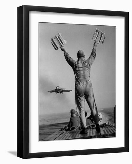 Shot of a Man Using Hand Lights to Signal an Incoming Aircraft Towards the Carrier's Landing-Hank Walker-Framed Photographic Print