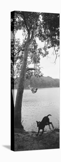 Side Profile of a Boy Swinging on a Rope Over a Lake-null-Stretched Canvas