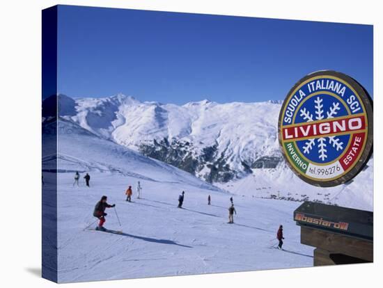 Sign with Skiers and Mountains in the Background at the Ski Resort of Livigno in Northern Italy-Teegan Tom-Stretched Canvas