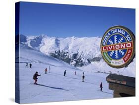 Sign with Skiers and Mountains in the Background at the Ski Resort of Livigno in Northern Italy-Teegan Tom-Stretched Canvas