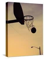 Silhouette of a Basketball Going Through a Basketball Net-null-Stretched Canvas