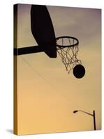 Silhouette of a Basketball Going Through a Basketball Net-null-Stretched Canvas