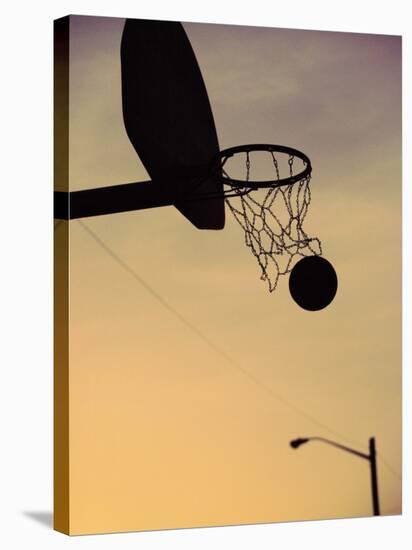 Silhouette of a Basketball Going Through a Basketball Net-null-Stretched Canvas