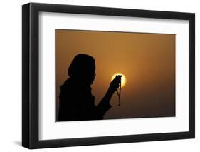 Silhouette of a Muslim woman holding prayer beads in her hands and praying at sunset-Godong-Framed Photographic Print