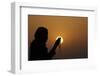 Silhouette of a Muslim woman holding prayer beads in her hands and praying at sunset-Godong-Framed Photographic Print