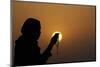 Silhouette of a Muslim woman holding prayer beads in her hands and praying at sunset-Godong-Mounted Photographic Print