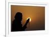 Silhouette of a Muslim woman holding prayer beads in her hands and praying at sunset-Godong-Framed Photographic Print