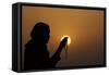 Silhouette of a Muslim woman holding prayer beads in her hands and praying at sunset-Godong-Framed Stretched Canvas