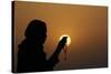 Silhouette of a Muslim woman holding prayer beads in her hands and praying at sunset-Godong-Stretched Canvas