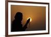 Silhouette of a Muslim woman holding prayer beads in her hands and praying at sunset-Godong-Framed Photographic Print