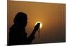 Silhouette of a Muslim woman holding prayer beads in her hands and praying at sunset-Godong-Mounted Photographic Print