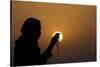 Silhouette of a Muslim woman holding prayer beads in her hands and praying at sunset-Godong-Stretched Canvas