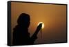 Silhouette of a Muslim woman holding prayer beads in her hands and praying at sunset-Godong-Framed Stretched Canvas