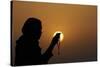 Silhouette of a Muslim woman holding prayer beads in her hands and praying at sunset-Godong-Stretched Canvas