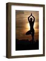 Silhouette of a woman in Vrkasana (tree pose) practising yoga against the light of the evening sun-Godong-Framed Photographic Print