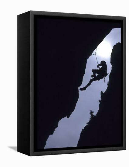 Silhouette of Rock Climber Hanging from Cliff Face-null-Framed Stretched Canvas
