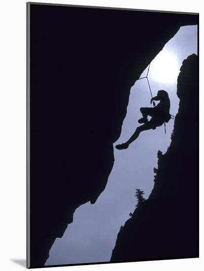Silhouette of Rock Climber Hanging from Cliff Face-null-Mounted Photographic Print